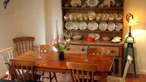 A dining area with a wooden table and chairs, a vase with flowers, and a shelf with plates and bowls. - Great location to explore Connemara (Connemara)