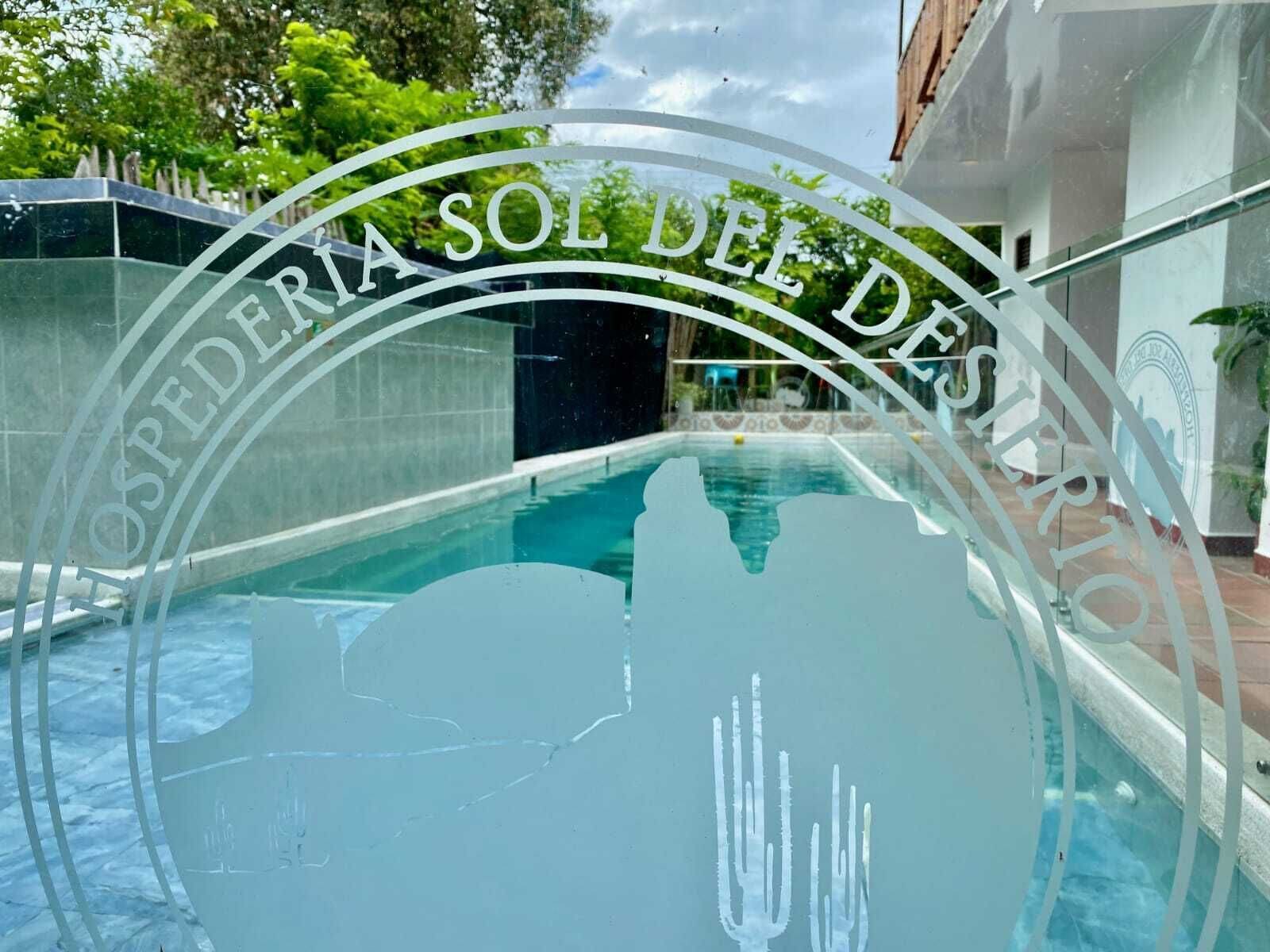 A swimming pool with a glass enclosure and a sign reading "OSPEDERIA SOL DE DES."