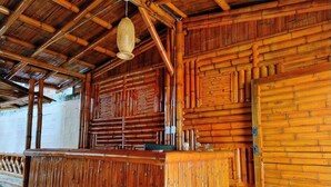 A bamboo-themed interior with a central wooden counter and a woven hanging light fixture. - Hospedería Sol Del Desierto - Hostel (Villavieja)