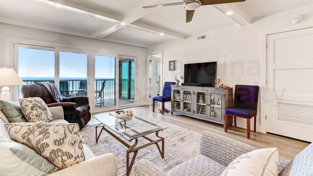 A spacious living room with a glass coffee table, leather sofa, and a television on a cabinet.