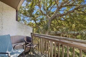 A balcony with a wooden railing, a chair, and a sofa. - Dog Friendly Forest Ridge Condo Close to Beach by RedAwning (Fernandina Beach)