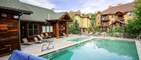 A pool area with lounge chairs and a wooden cabin structure.
