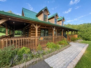 Un chalet en bois doté d’un porche couvert et d’un chemin de pierre menant à l’entrée.