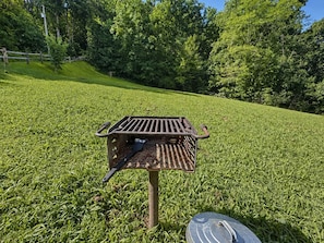 A metal bird feeder on a grassy hill with trees in the background. - Dogwood Acre 3 Bedroom Cabin by RedAwning (Sevierville)