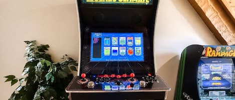 A retro arcade machine with a selection of games, including Asteroids and Space Invaders, and a plant in the background.