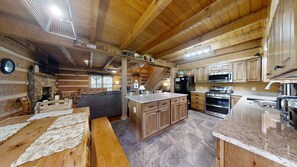 Ein Holzhütten-Interieur mit Küche, Essbereich und Kamin.