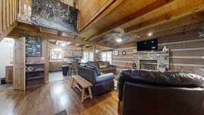 A rustic cabin interior with a living room, kitchen, and dining area.