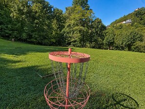 A disc golf basket in a grassy field with trees and a hill in the background. - Dogwood Acre 3 Bedroom Cabin by RedAwning (Sevierville)