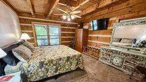 A bedroom with a bed, a dresser, a television, and a ceiling fan. - Dogwood Acre 3 Bedroom Cabin by RedAwning (Sevierville)