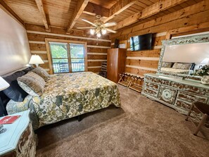 A bedroom with a bed, a dresser, a television, and a ceiling fan. - Dogwood Acre 3 Bedroom Cabin by RedAwning (Sevierville)