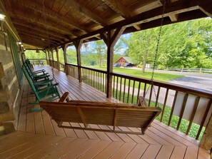 A covered porch with wooden benches and a swing.