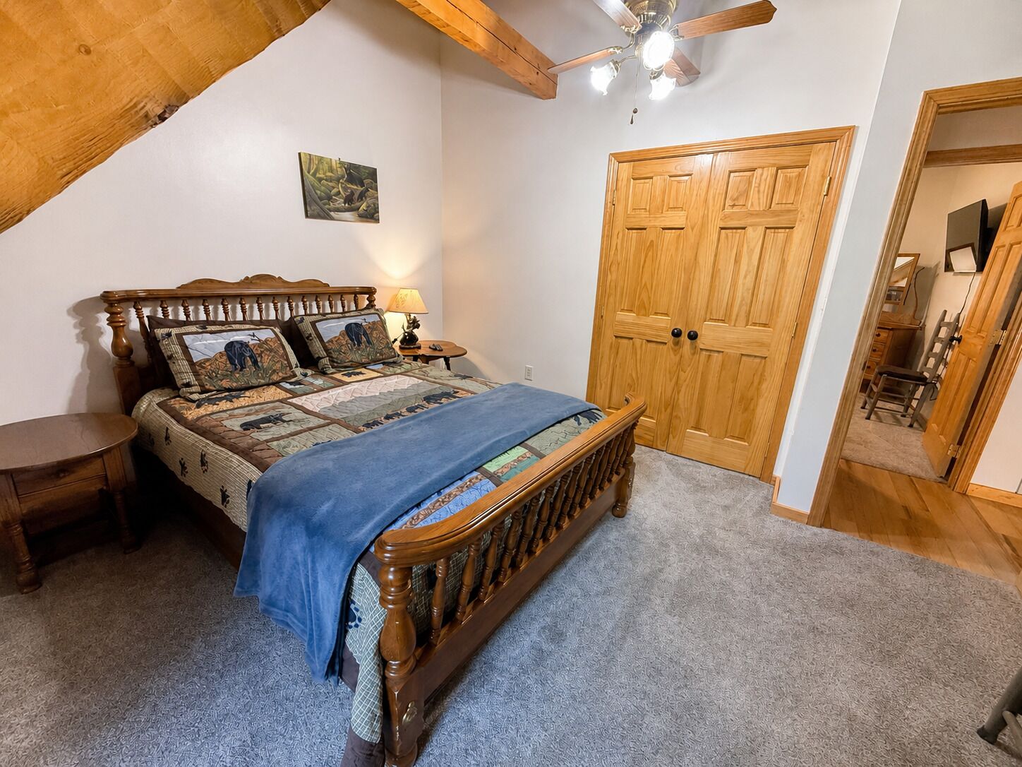 A bedroom with a wooden bed, a nightstand, a ceiling fan, and a wooden wardrobe.