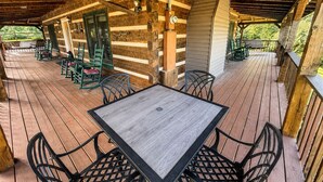 A covered outdoor area with a wooden deck, a table with chairs, and a hanging light fixture. - Dogwood Acre 3 Bedroom Cabin by RedAwning (Sevierville)