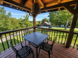 Une terrasse extérieure couverte, dotée d’une table et de chaises, qui offre une vue sur un quartier résidentiel avec une maison et une route.