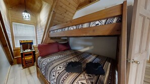 A bunk bed with patterned bedding, a small table with a lamp, and a window with blinds. - Dogwood Acre 3 Bedroom Cabin by RedAwning (Sevierville)