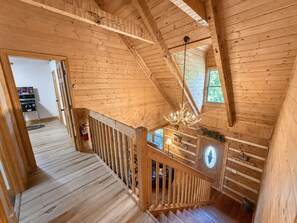 Interior de madera con una escalera, paredes de madera, una lámpara de araña y un extintor.