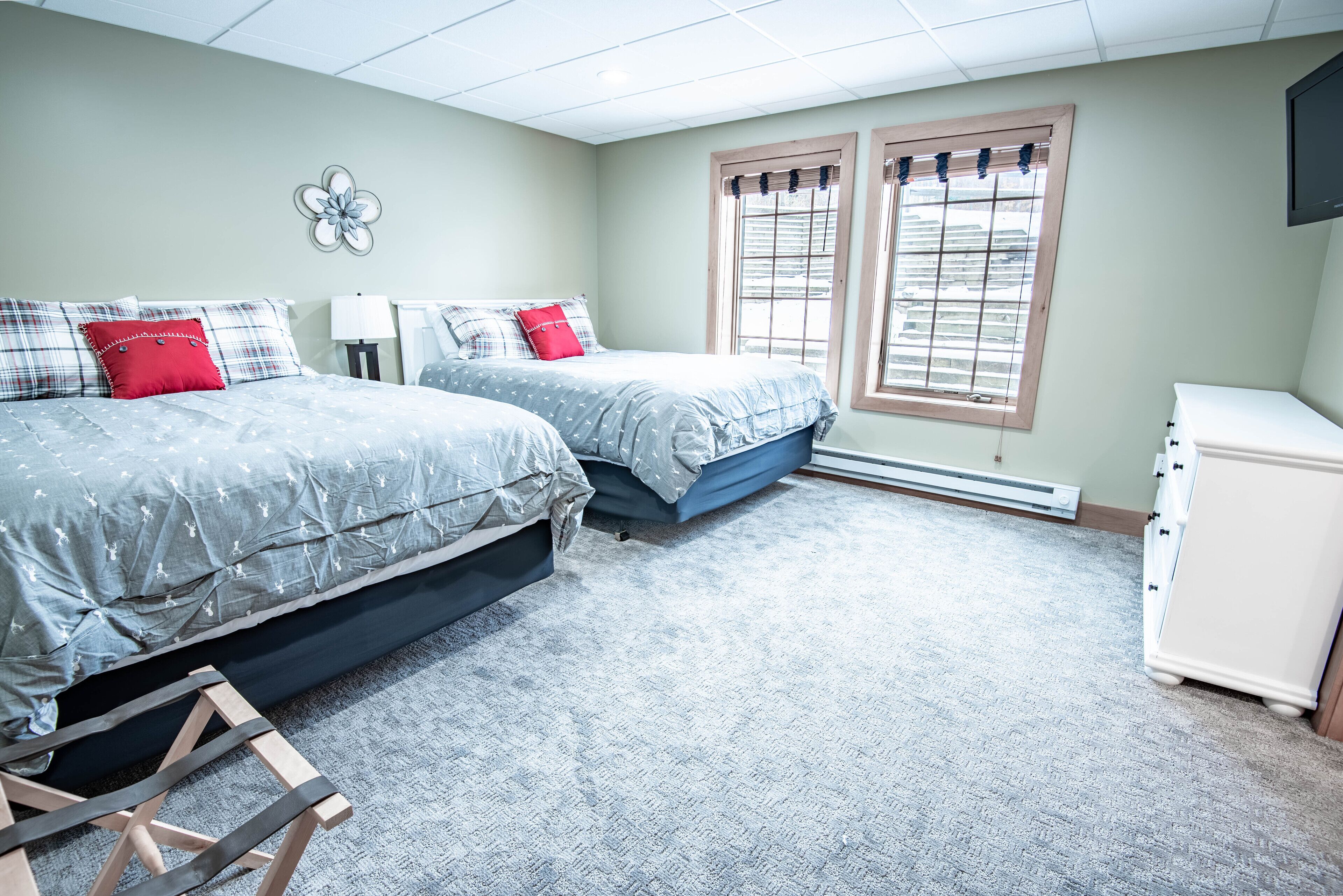 A bedroom with two beds, a dresser, and a radiator.