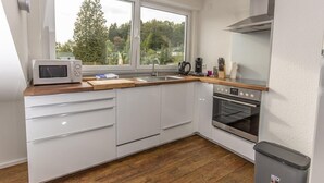 Uma cozinha moderna com armários brancos, micro-ondas, cafeteira e forno.