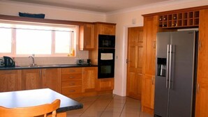 Eine Küche mit Holzausstattung, einem Edelstahlkühlschrank und einem Fenster, das für natürliches Licht sorgt.