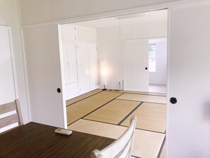 A room with tatami flooring, a wooden table, and a chair.