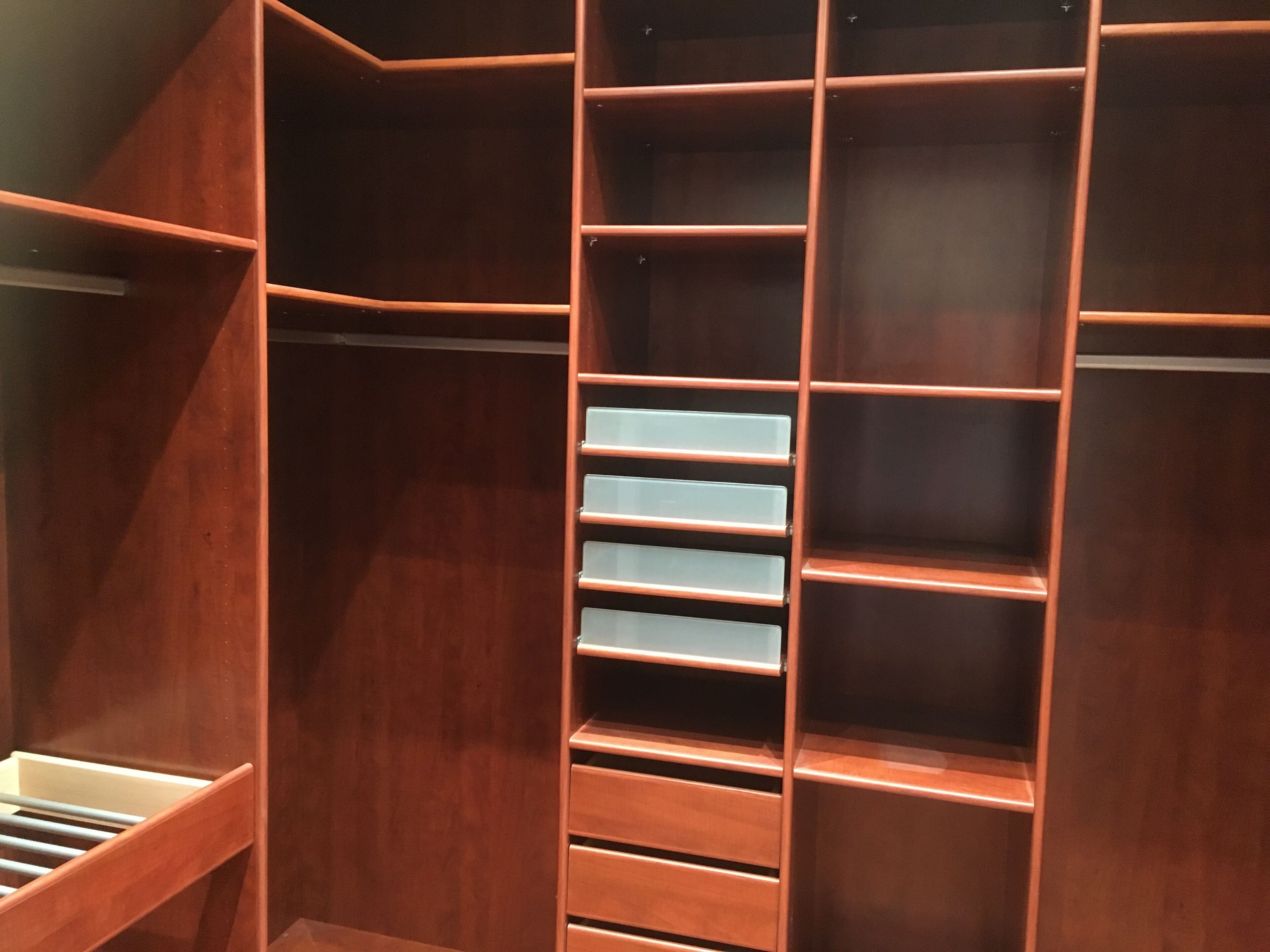 A wooden closet with multiple shelves and drawers.