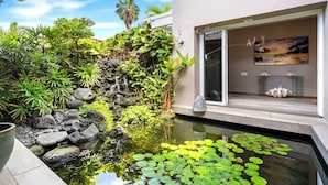 Un jardín tranquilo con un estanque, abundante vegetación y una cascada.