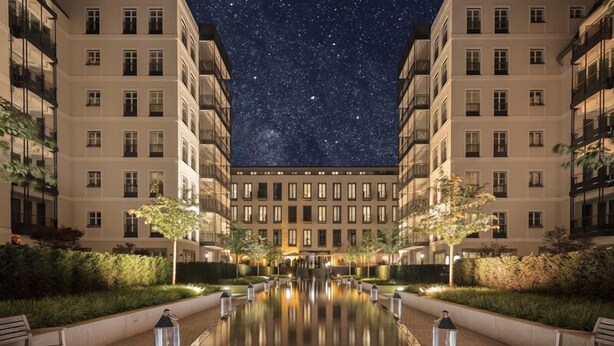 Un patio de hotel nocturno con cielo estrellado, un estanque reflectante y una fachada de edificio simétrica.