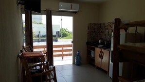 A room with a dining table and chairs, a kitchen area with cabinets, and a sliding glass door leading to an outdoor area.
