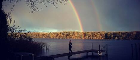 A person standing on a dock with a rainbow in the background.