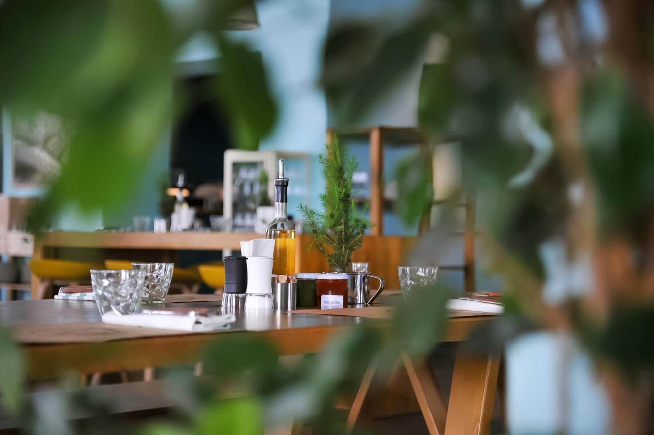 A dining table with various items including a small potted plant, a glass bowl, and a bottle.