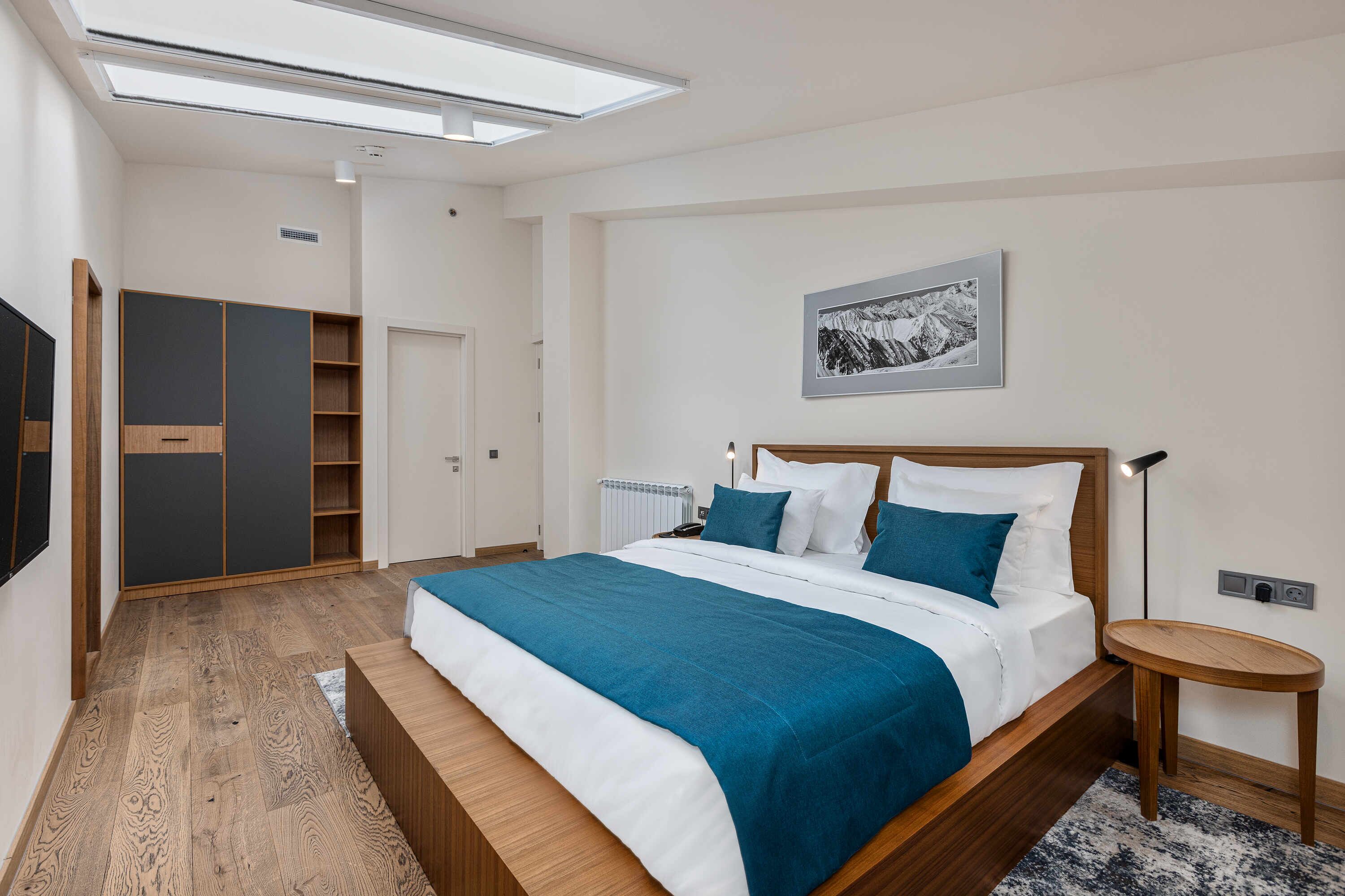 Un dormitorio moderno con una cama grande, un armario, un radiador y un cuadro enmarcado en la pared.