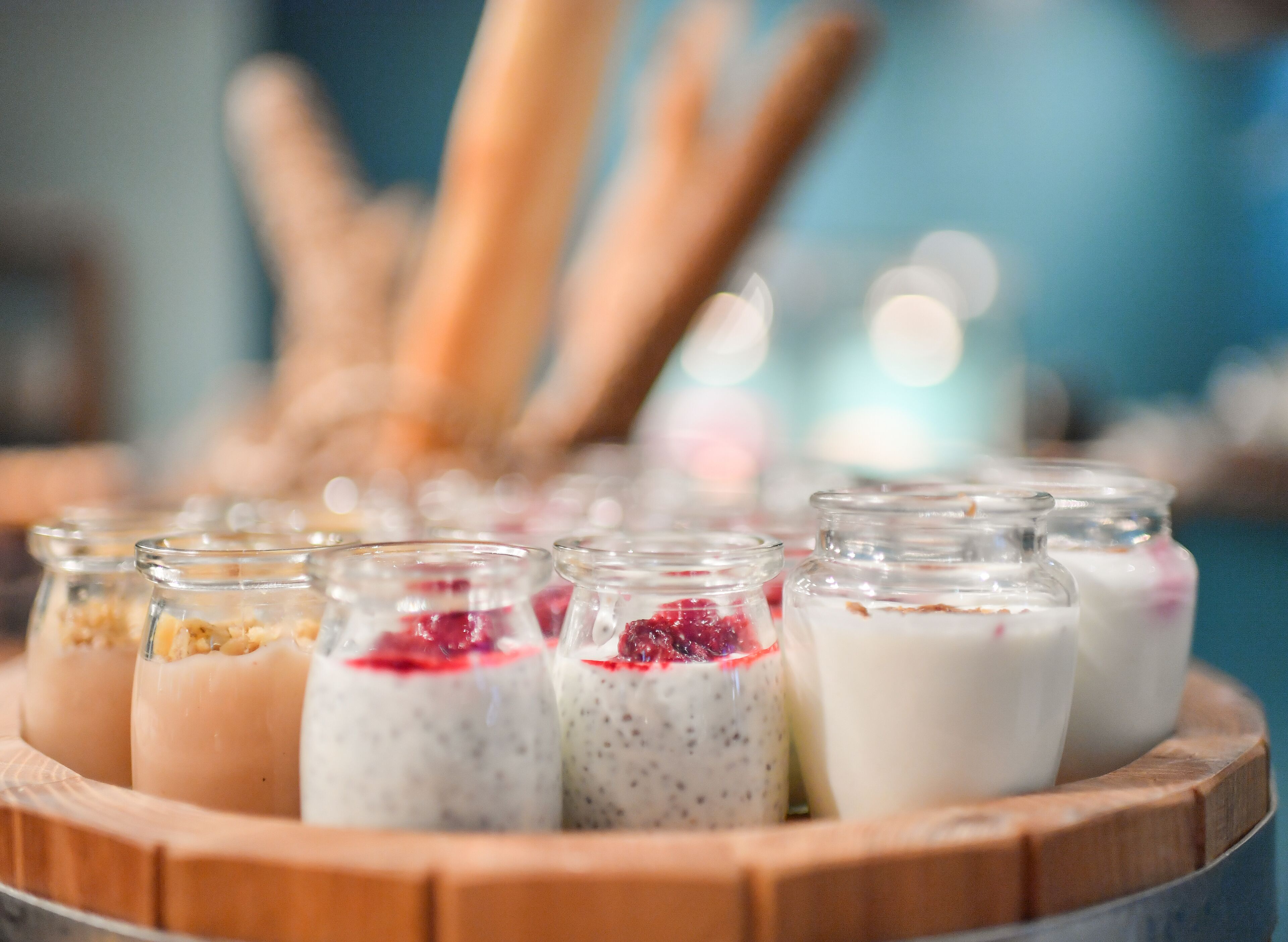 A wooden tray with glass jars containing various food items.