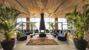 A spacious lobby with a wooden ceiling, large windows, and multiple seating areas. - Gudauri Lodge (Kazbegi)