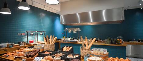 A bakery counter with various baked goods and a coffee station.