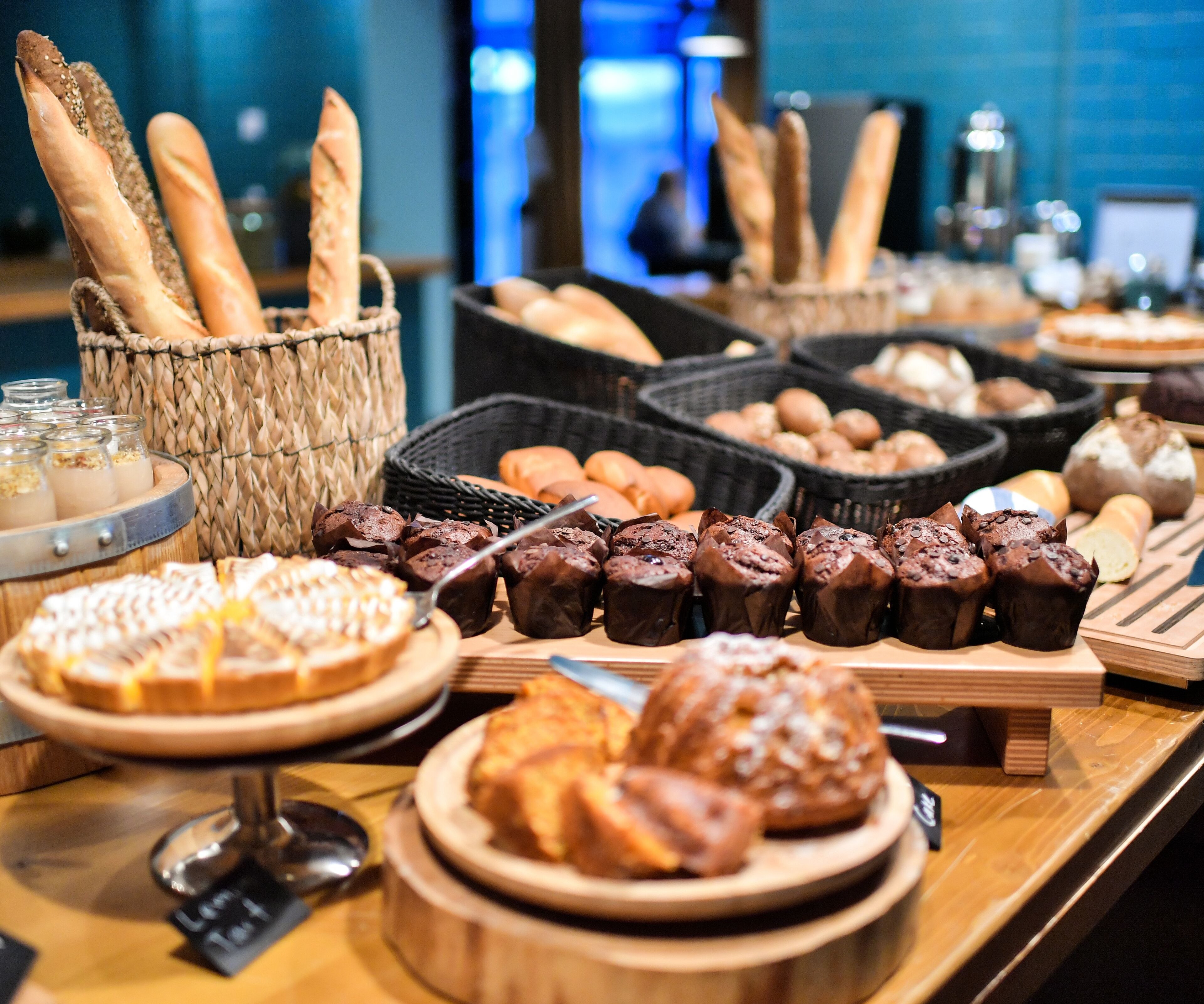 A buffet with various baked goods including bread, muffins, and pastries.