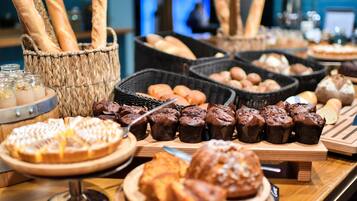 A buffet with various baked goods including bread, muffins, and pastries.
