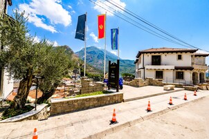 A building with a tiled roof, a stone wall, and a flagpole with multiple flags.