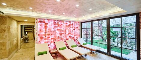 Une salle de spa équipée de quatre chaises longues, d’une table de massage et d’une grande fenêtre donnant sur l’extérieur.