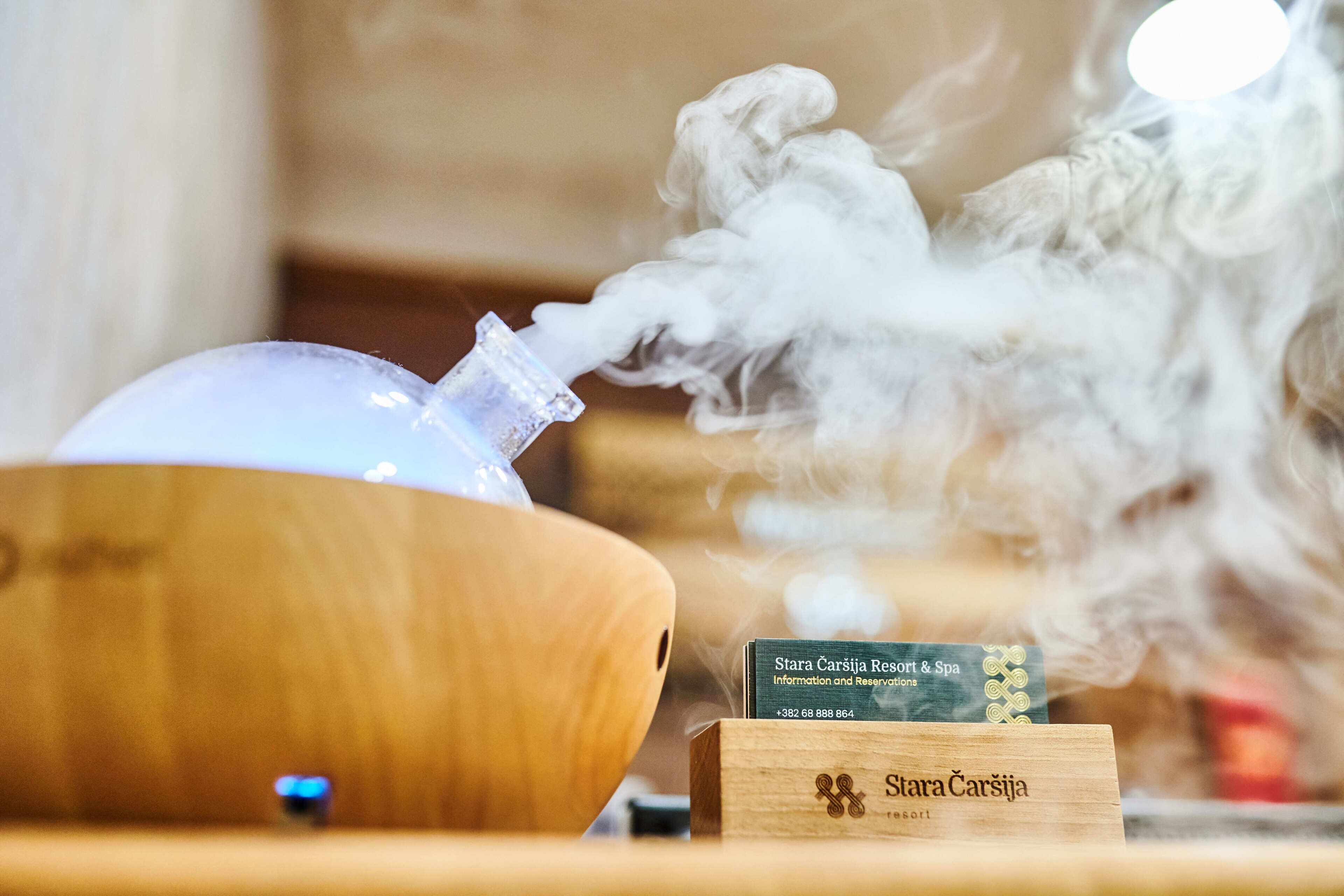 A wooden bowl, a glass container with smoke, and a wooden sign with the text "Stara Caršićia Resort & Spa".