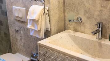 A bathroom with a sink, towel rack, soap dispenser, and a toilet.