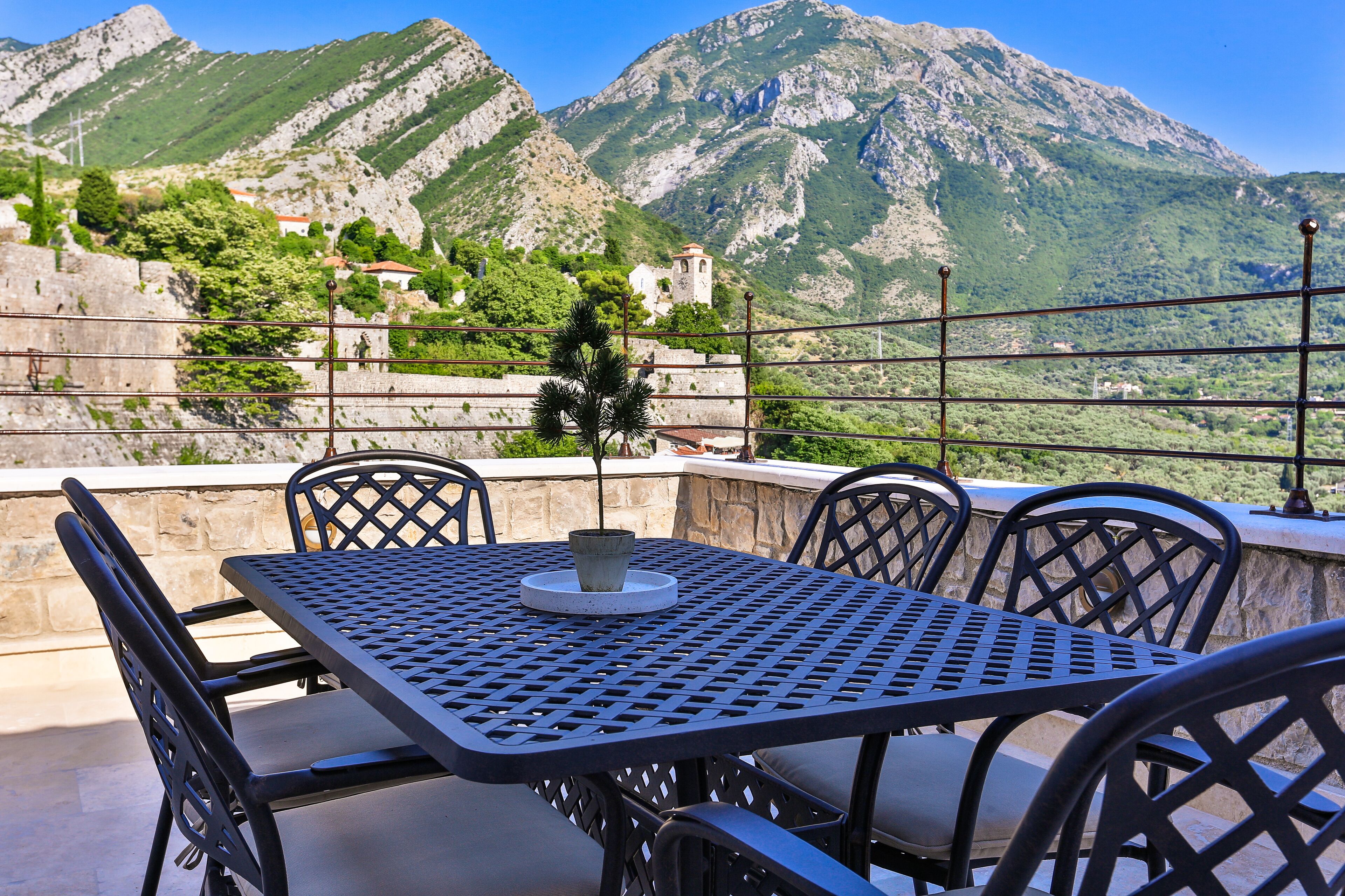 A table and chairs on an outdoor terrace with a mountain view.
