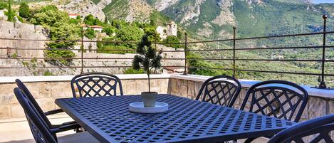 A table and chairs on an outdoor terrace with a mountain view.