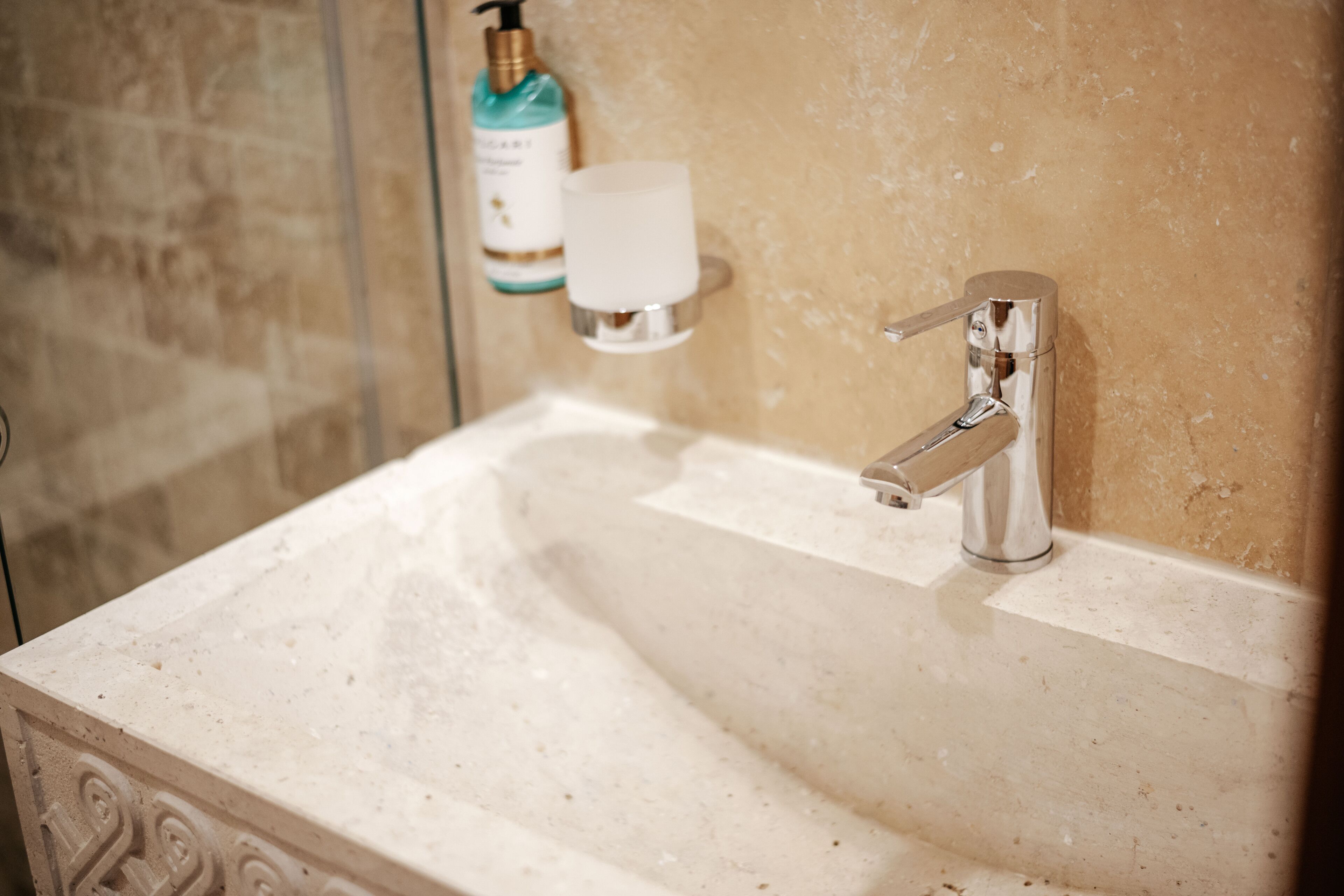 A bathroom sink with a chrome faucet, a soap dispenser, and a soap dish.