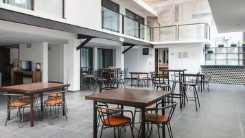 Un vaste espace intérieur doté de nombreuses tables et chaises, d’un escalier et d’une architecture moderne.