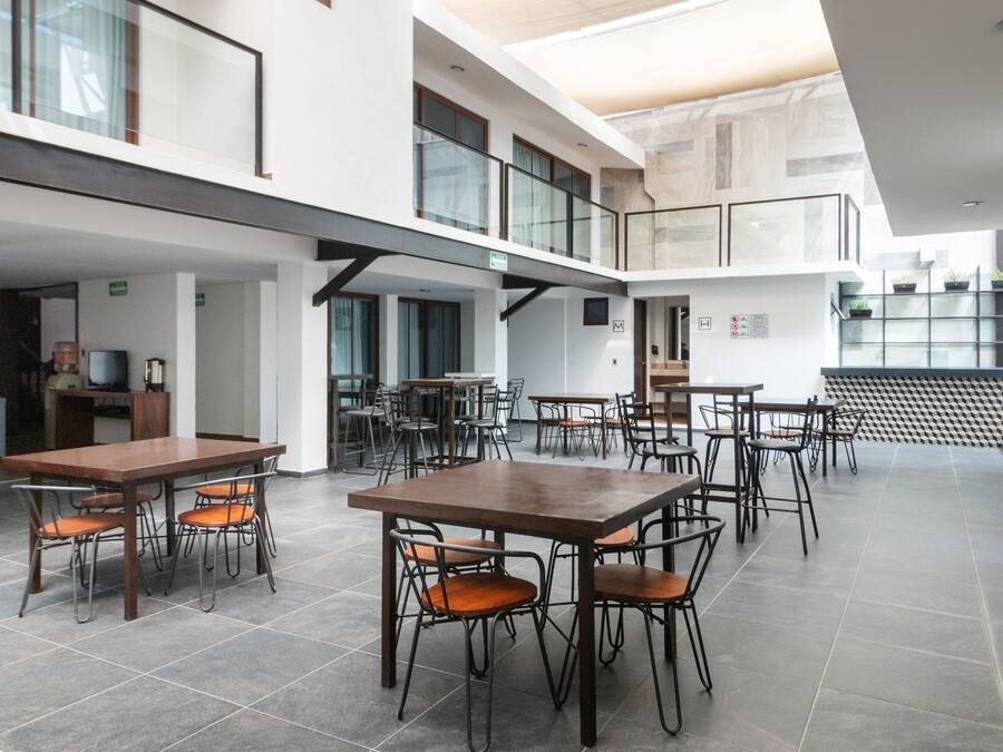 Un vaste espace intérieur doté de nombreuses tables et chaises, d’un escalier et d’une architecture moderne.