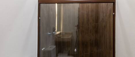A modern bathroom with a glass-enclosed shower, a toilet, and a sink.