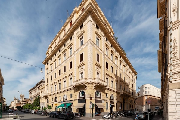 A corner building with a classic architectural style, featuring multiple windows and a prominent entrance.