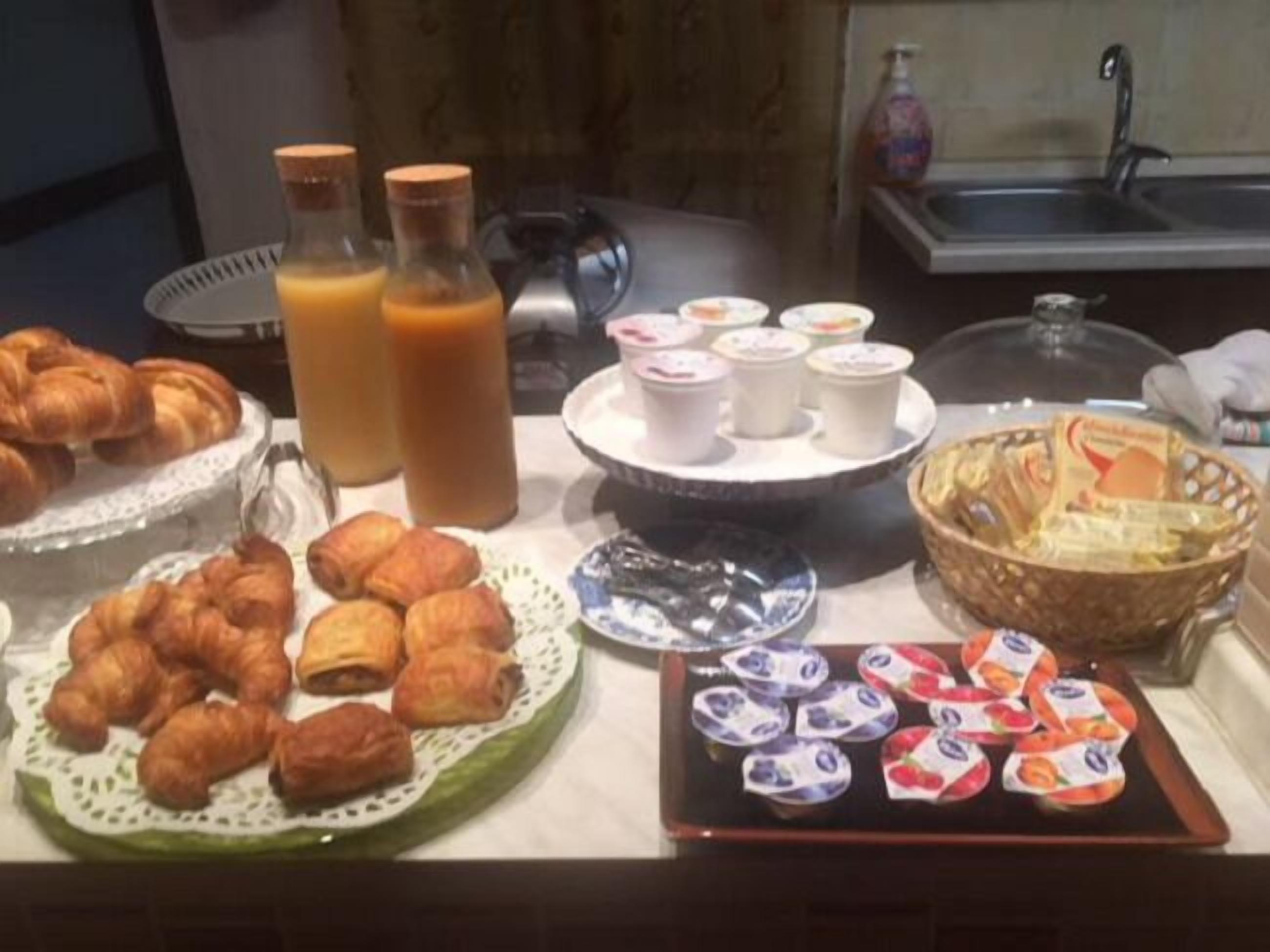 Un bufé de desayuno con cruasanes, pasteles, fruta y jugo.