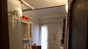 Een badkamer met douche, wastafel, toilet en een klein raam.