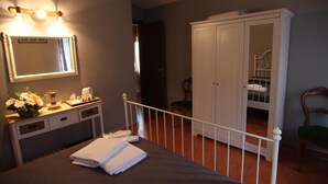 Een slaapkamer met een bed, nachtkastje, spiegel, kledingkast en een stoel.